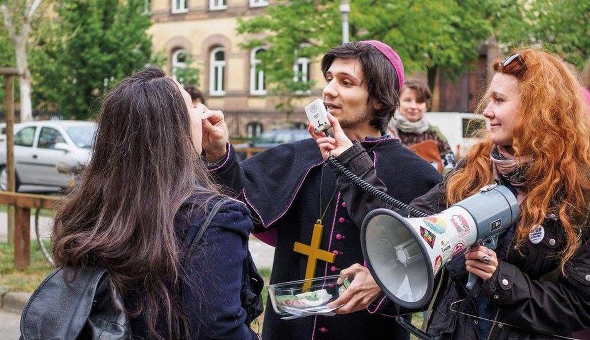 2016-ban a budapesti lengyel nagykövetség előtt az abortusztörvény tervezett szigorítása elleni tiltakozáson aktivisták „abortusztablettával” áldoztatták a résztvevőket. <br> Fotó: 777blog.hu 