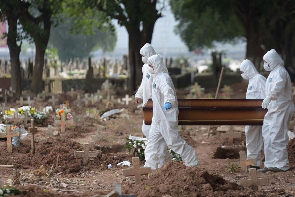 Rio de Janeiroban egy temető dolgozói tetőtől talpig védőöltözetben viszik a koronavírusban elhunytak koporsóit tavaly áprilisban. <br> Fotó: Shutterstock