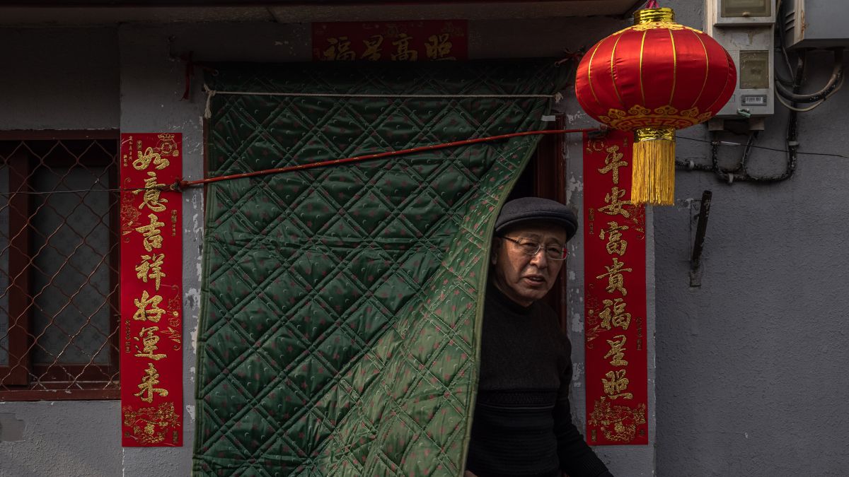 A holdújévre feldíszített házából néz ki egy férfi Peking Hutung negyedében 2021. február 11-én, a legnagyobb kínai ünnep előestéjén. (MTI/EPA/Roman Pilipej)