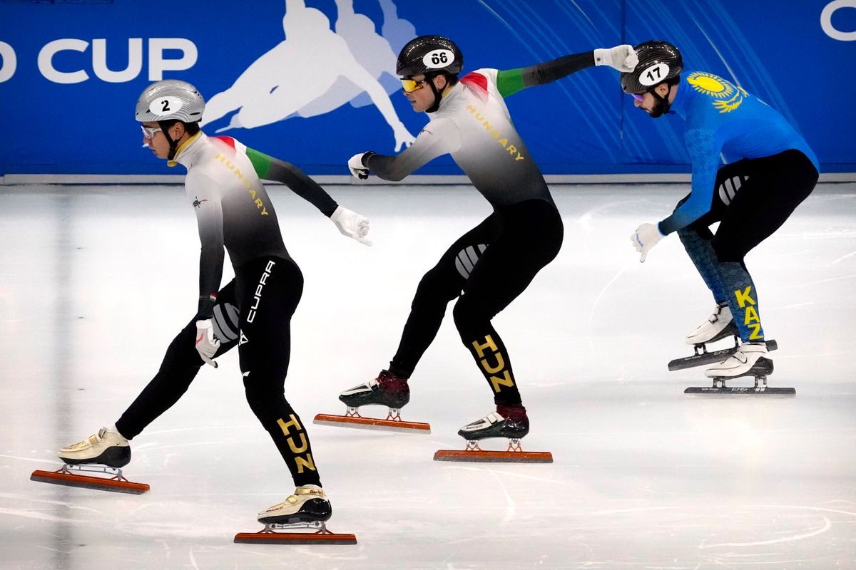 Rueger John-Henry (középen), Liu Shaolin Sándor (balra) és a kazah Denisz Nikisa célba ér a rövid pályás gyorskorcsolya-világkupa pekingi viadala férfi 500 méteres versenyének döntőjében a Fővárosi Sportcsarnokban 2021. október 23-án. A viadal a 2022-es pekingi téli olimpia egyik teszteseménye volt. MTI/AP/Mark Schiefelbein