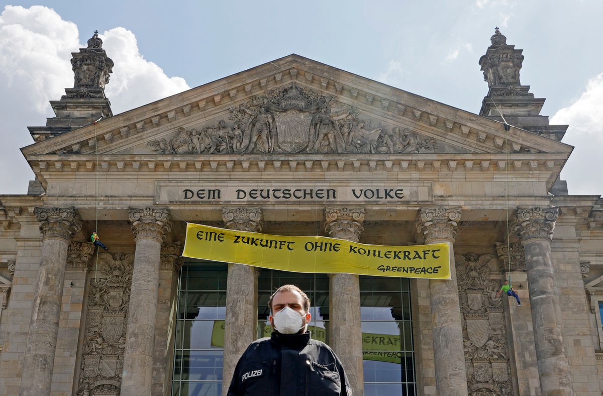 Tűzoltók eltávolítják a Greenpeace környezetvédő aktivisták által a német parlament homlokzatára függesztett „Szénenergia nélküli jövő" feliratú transzparenst Berlinben 2020. július 3-án. MTI/EPA/Ronald Wittek