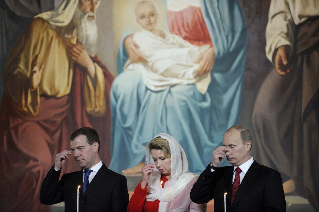 A belügyesek közül alighanem Dmitirj Medvegyev (b) jutott a legmagasabbra, hiszen ő egy darabig Putyin dublőreként is tevékenykedhetett. Medvegyev a legkorábbi és leghűségesebb Putyin-fiókák egyike, vagyis nem is kifejezetten „barát”, hanem inkább „fiú”. A képen feleségével, Szvetlánával (k) és Putyinnal látható egy húsvéti misén a moszkvai Megváltó Krisztus-székesegyházban, 2010-ben. Fotó: NATALIA KOLESNIKOVA / AFP