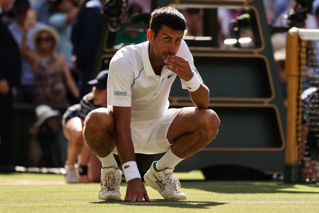 Novak Djokovic hetedszer is előadhatta győzelmi rituáléját, a wimbledoni gyep megkóstolását. Fotó: Adrian Dennis / AFP