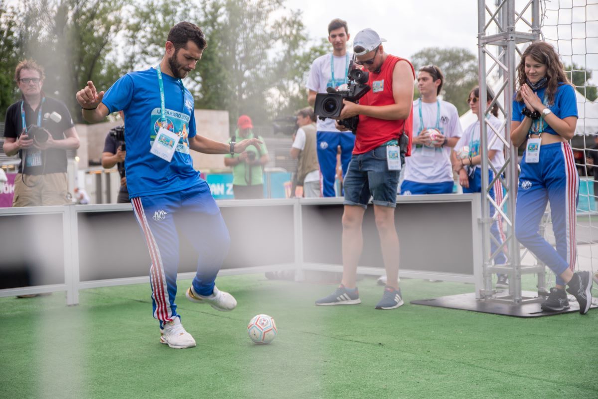 Egy görög önkéntes lő kapura csukott szemmel, csörgőlabdával a városligeti szurkolói zónában, 2021. június 21-én.<br>Fotó: EURO 2020 Hivatalos szurkolói zóna.