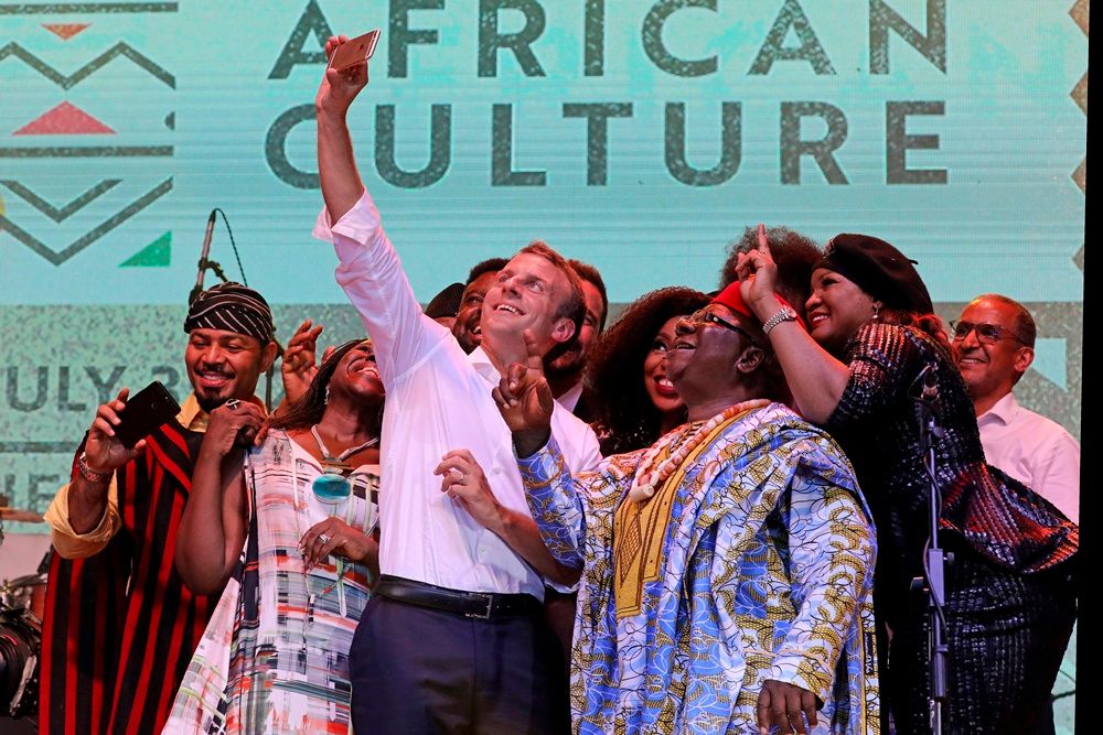 Emmanuel Macron nigériai előadóművészekkel fényképezkedik a Lagos délnyugati nagyváros közelében levő New Afrika Shrine kulturális központban 2018. július 3-án. (MTI/EPA/AFP/Ludovic Marin/pool)