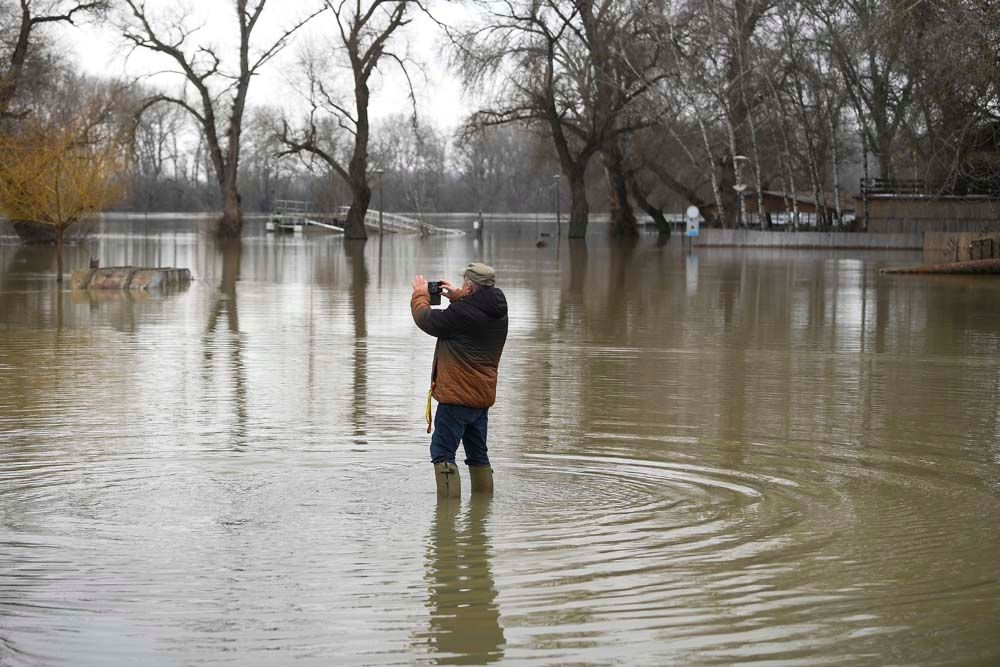 Tiszacsege, 2021. február 17. Egy férfi fényképezi telefonjával az áradó Tisza miatt elöntött partszakaszt a tiszacsegei kompnál 2021. február 17-én. <br>Fotó: MTI/Czeglédi Zsolt