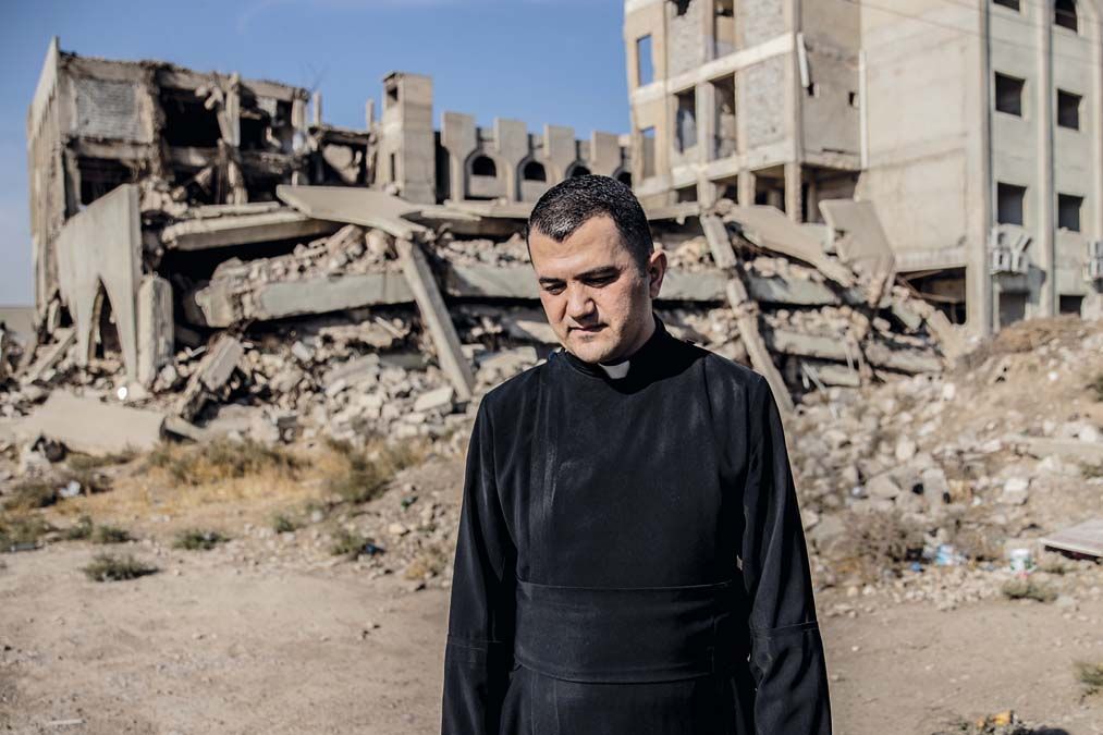 Egy lebombázott iraki egyetem, előtte a karakosi püspök titkára. <br> Fotó: Csudai Sándor
