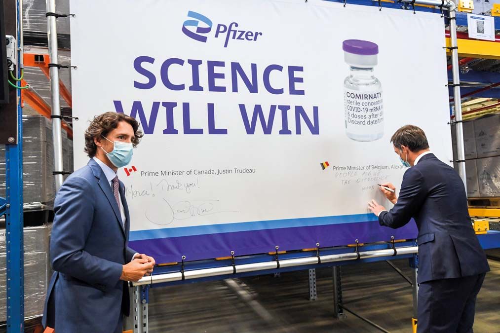 Justin Trudeau kanadai miniszterelnök és Alexander De Croo belga kormányfő aláírja a Pfizer gyógyszeripari vállalat koronavírus elleni  oltóanyagát reklámozó transzparenst a Pfizer üzemében a belgiumi Puursban 2021 júniusában. <br> Fotó: MTI / AP / Isopix pool / Frederic Sierakowski