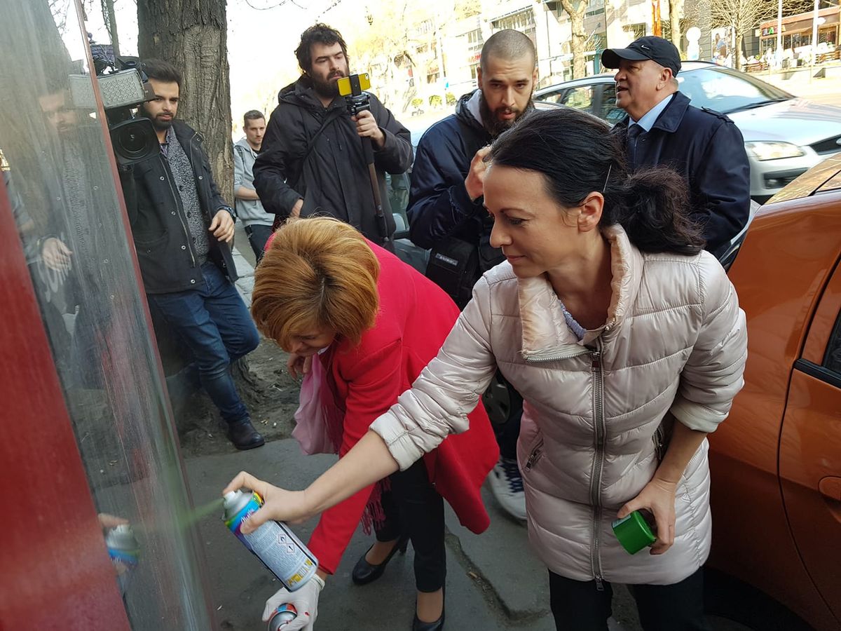 Szabó és Bangóné Borbély Ildikó plakátokat fúj le festékszóróval az ellenzék 2019 március 4-i utcai randalírozásán. (Fotó:Szabó Tímea/Facebook)