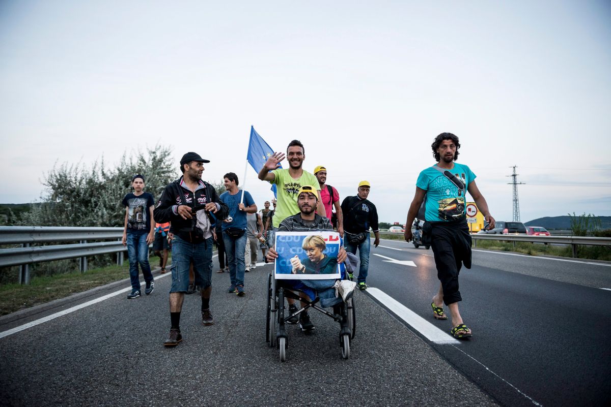 Angela Merkel képével vonulnak a menedékkérők az M1-es autópályán. Fotó: MTI/Bodnár Boglárka