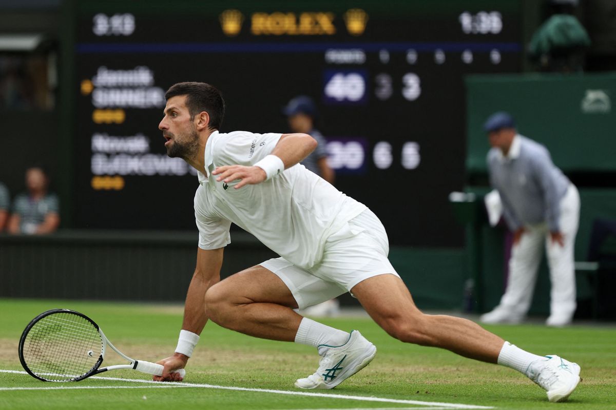 Serbia's Novak Djokovic slips on the grass as he tries to play a return against Italy's Jannik Sinner during their men's singles semi-finals tennis match on the twelfth day of the 2023 Wimbledon Championships at The All England Lawn Tennis Club in Wimbledon, southwest London, on July 14, 2023. (Photo by Adrian DENNIS / AFP) / RESTRICTED TO EDITORIAL USE