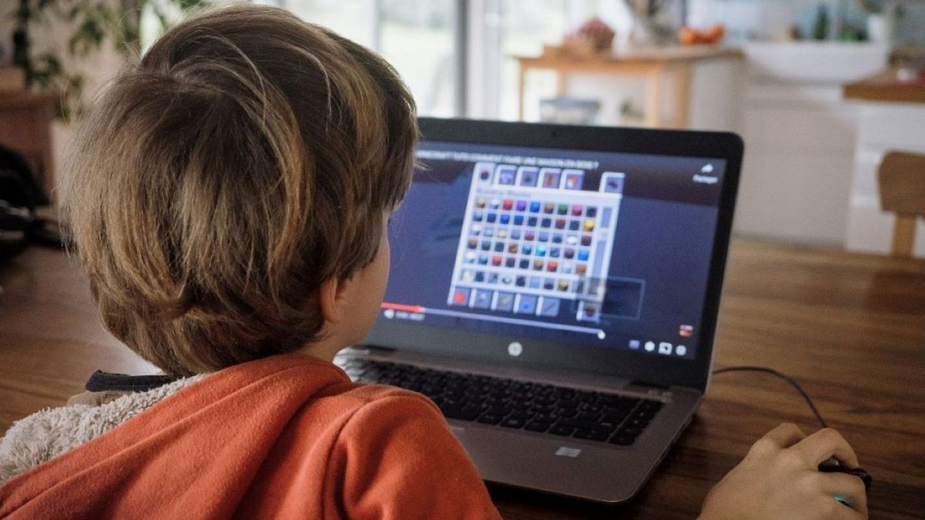 A 9 year-old child watches a video tutorial on Youtube on a computer to help him play Minecraft.