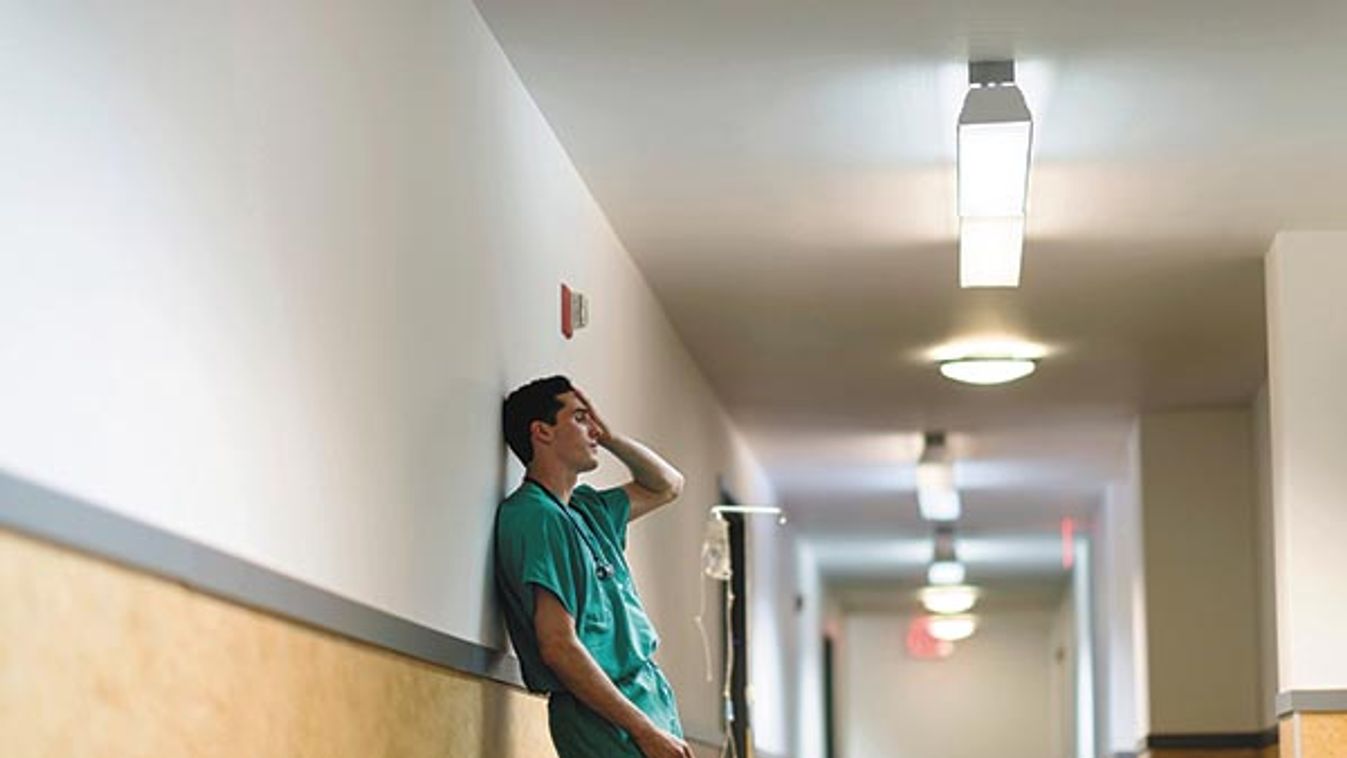 Tired doctor standing in hallway