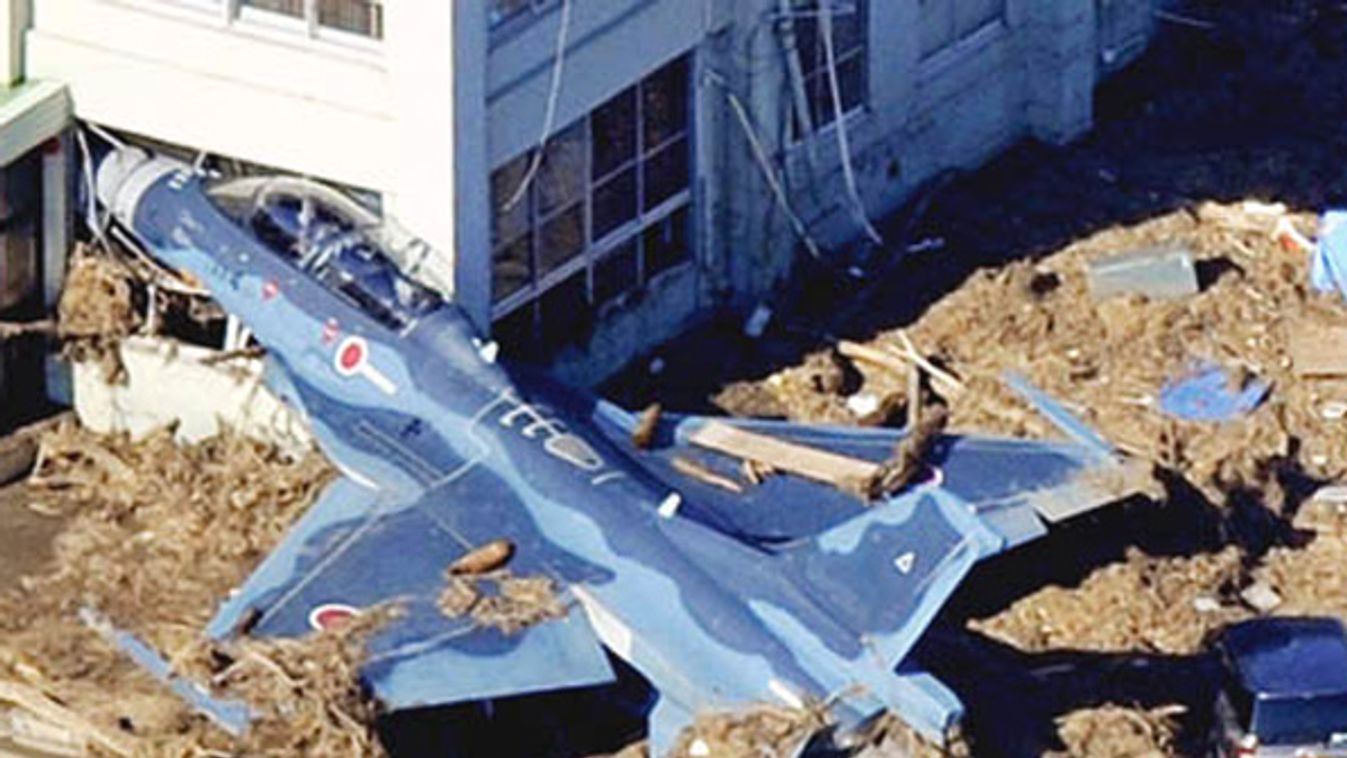 A Japan Self Defense Forces F-2 fighter jet is swept into a building by a tsunami at an airbase in Higashimatsushima City