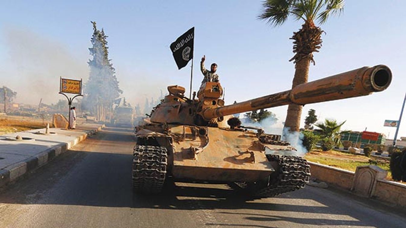 Militant Islamist fighters on a tank take part in a military parade along the streets of northern Raqqa province