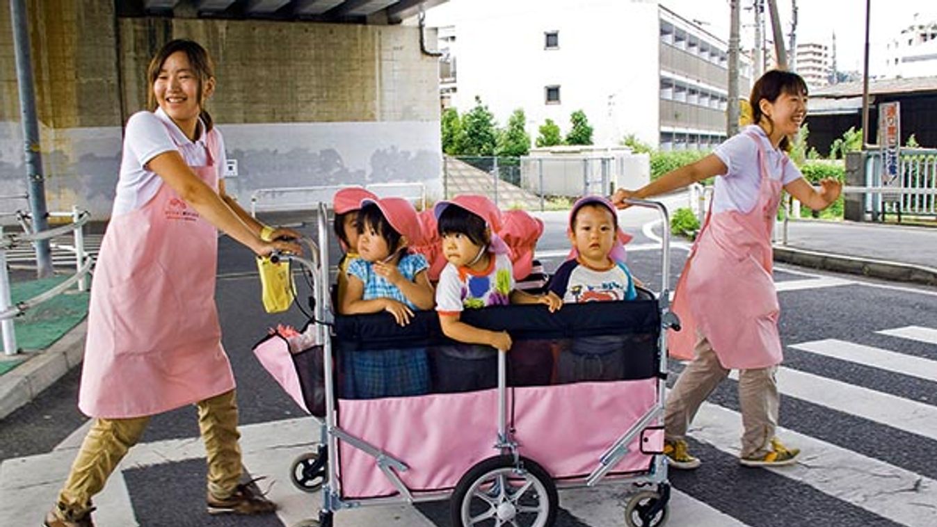 CHILDREN IN A STROLLER PULLED BY DAY CARE WORKERS ON A PEDESTRIAN CROSSING, TOKYO, JAPAN