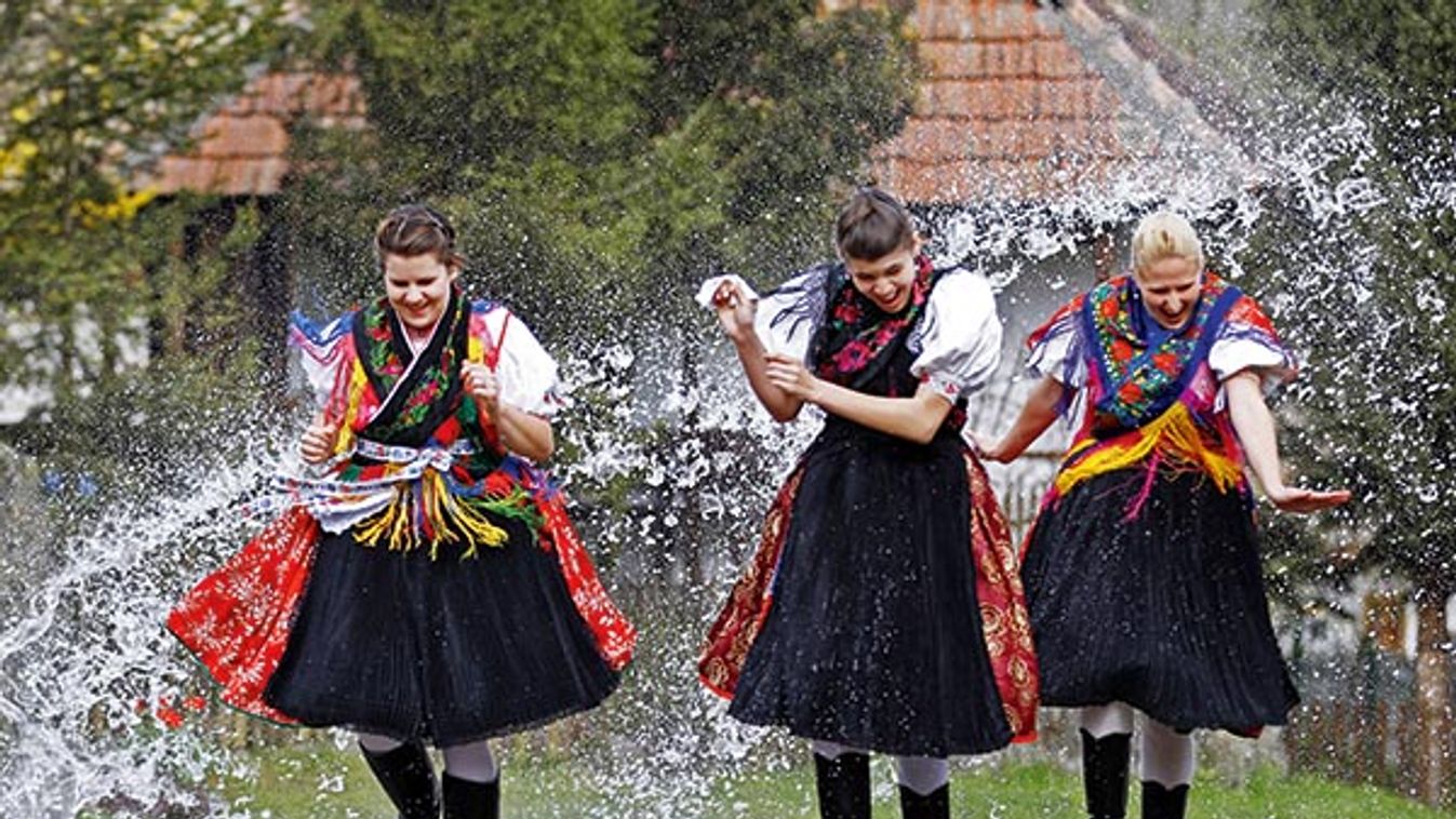 Women run while water is thrown at them as part of traditional Easter celebrations, during a media presentation in Holloko