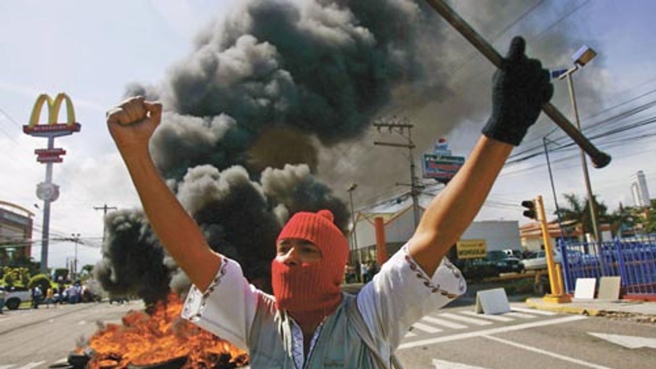 A supporter of Honduras' President Zelaya demonstrates in front of burning tires outside the presidential residency in Tegucigalpa