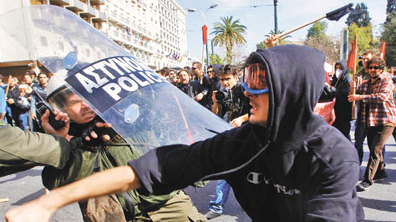 A protester clashes with riot policemen during an anti-government rally in Athens