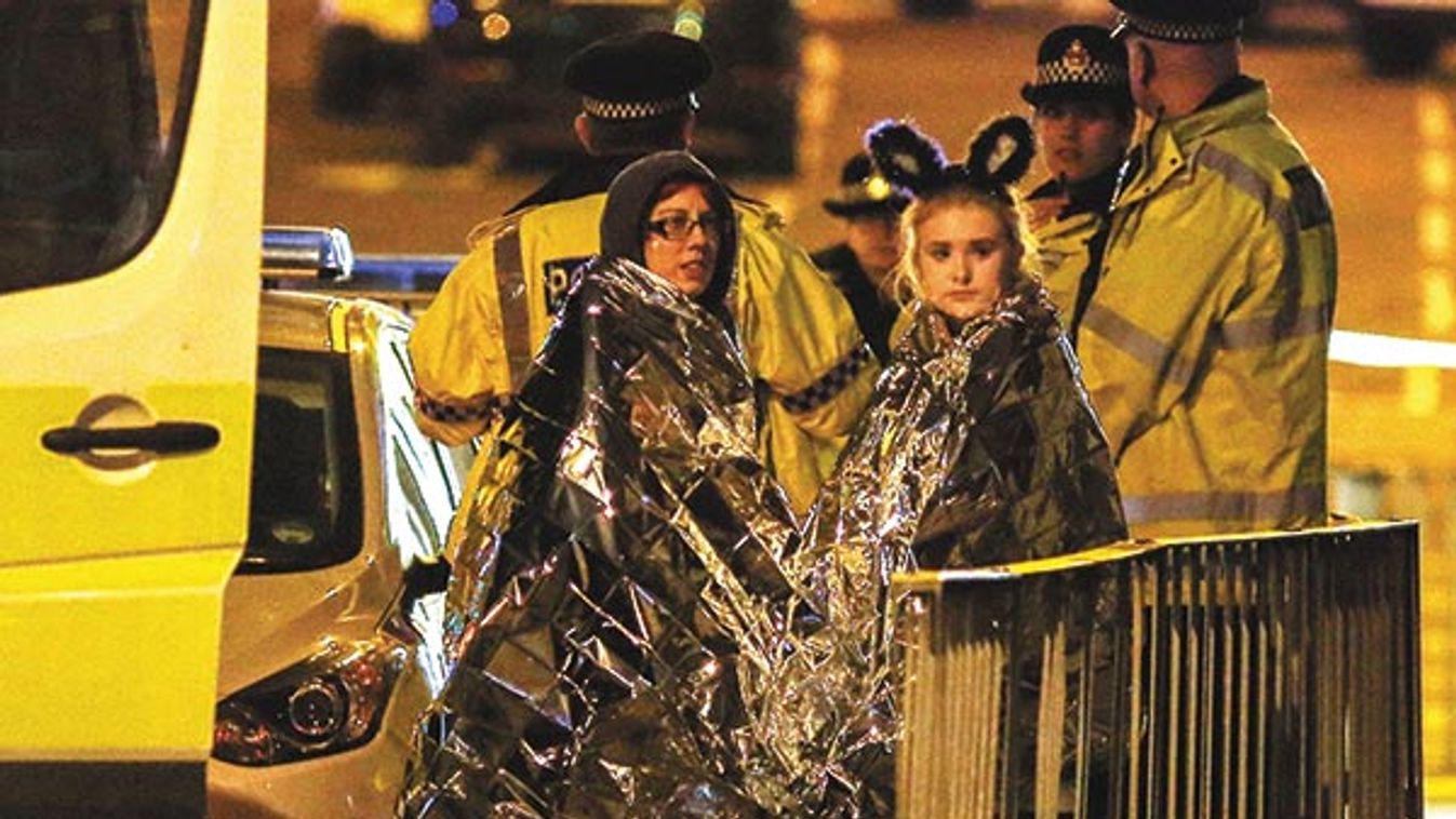 Two women wrapped in thermal blankets stand near the Manchester Arena, where U.S. singer Ariana Grande had been performing, in Manchester, northern England, Britain