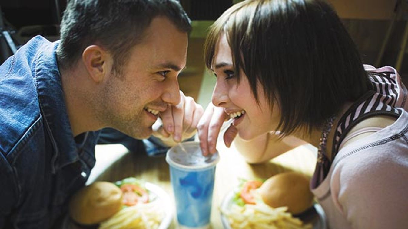 High angle view of a young man and a teenage girl looking at each other and drinking