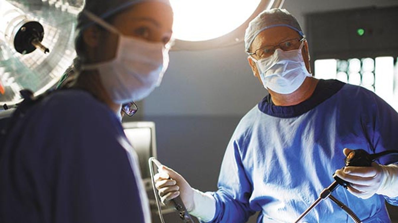 Male and female doctors performing laparoscopic surgery in operating theater