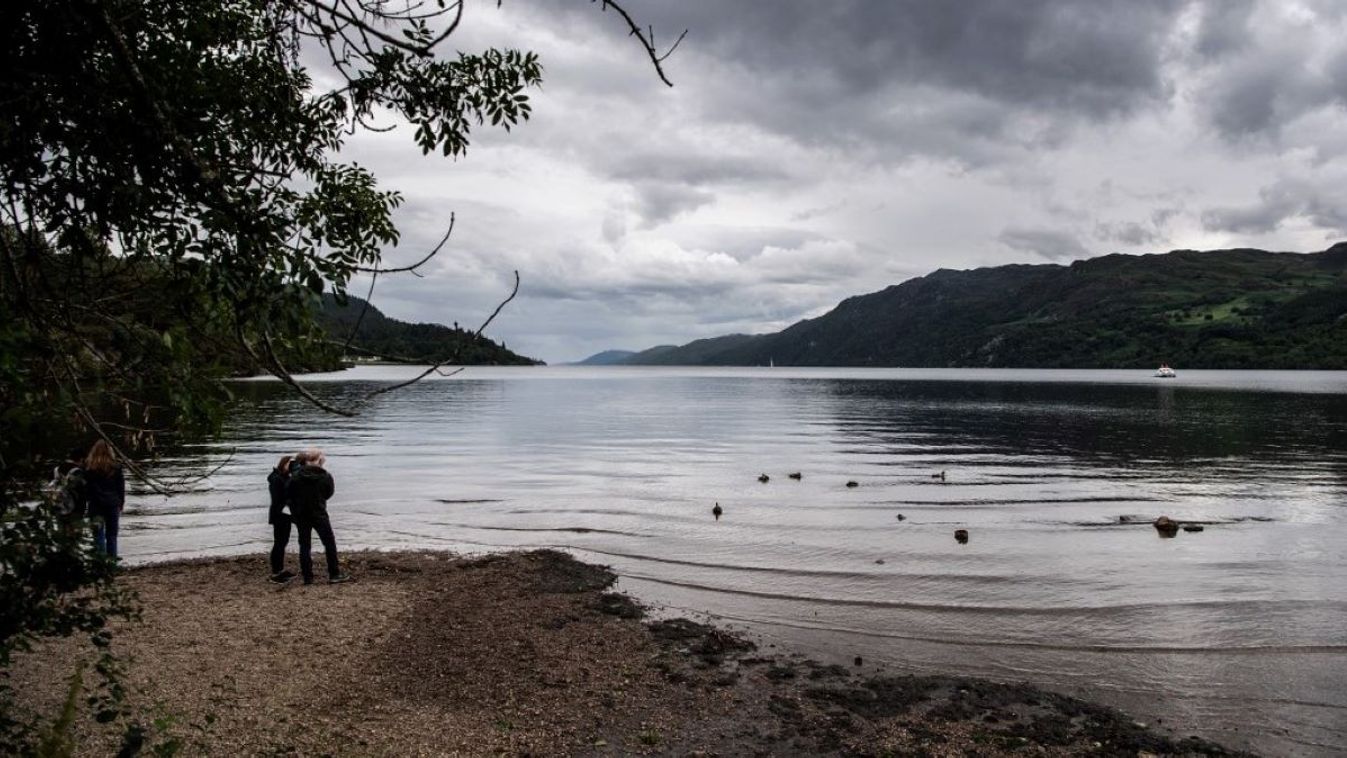 Visitors look at the water of Loch Ness, which is experiencing lower than average water level, on July 6, 2023, in the Scottish Highlands.