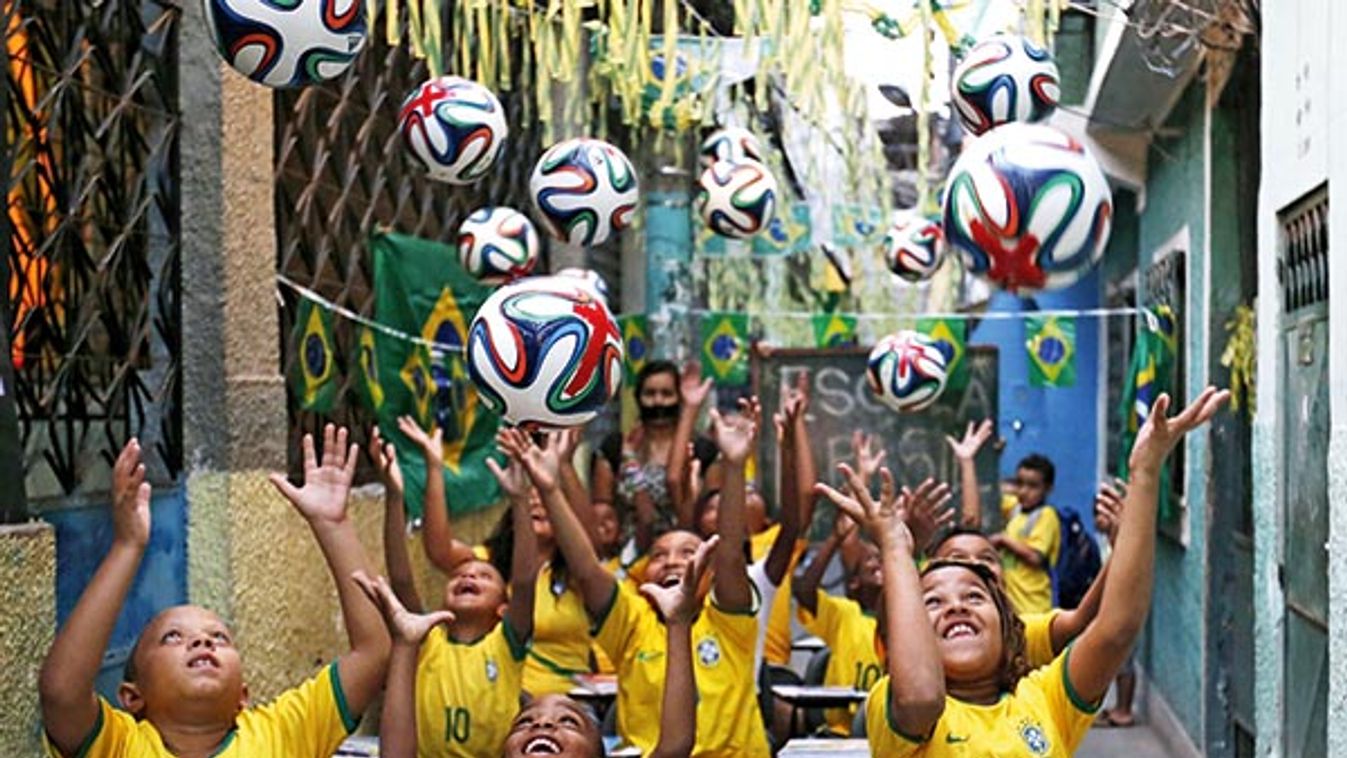 Children throw official 2014 FIFA World Cup soccer balls into the air, during a protest against 2014 World Cup, at the Jacarezinho slum in Rio de Janeiro