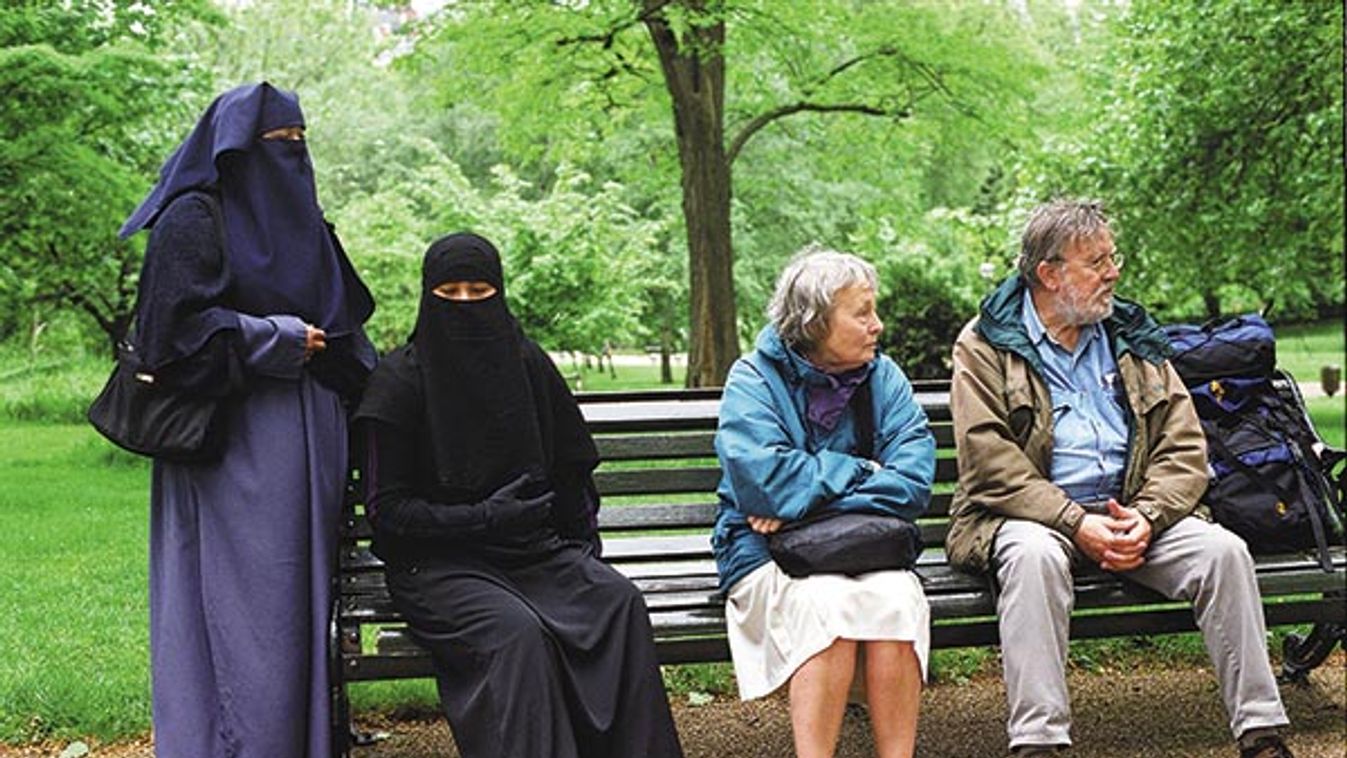 Muslim women sitting on a bench in Hyde Park London alongside an English couple