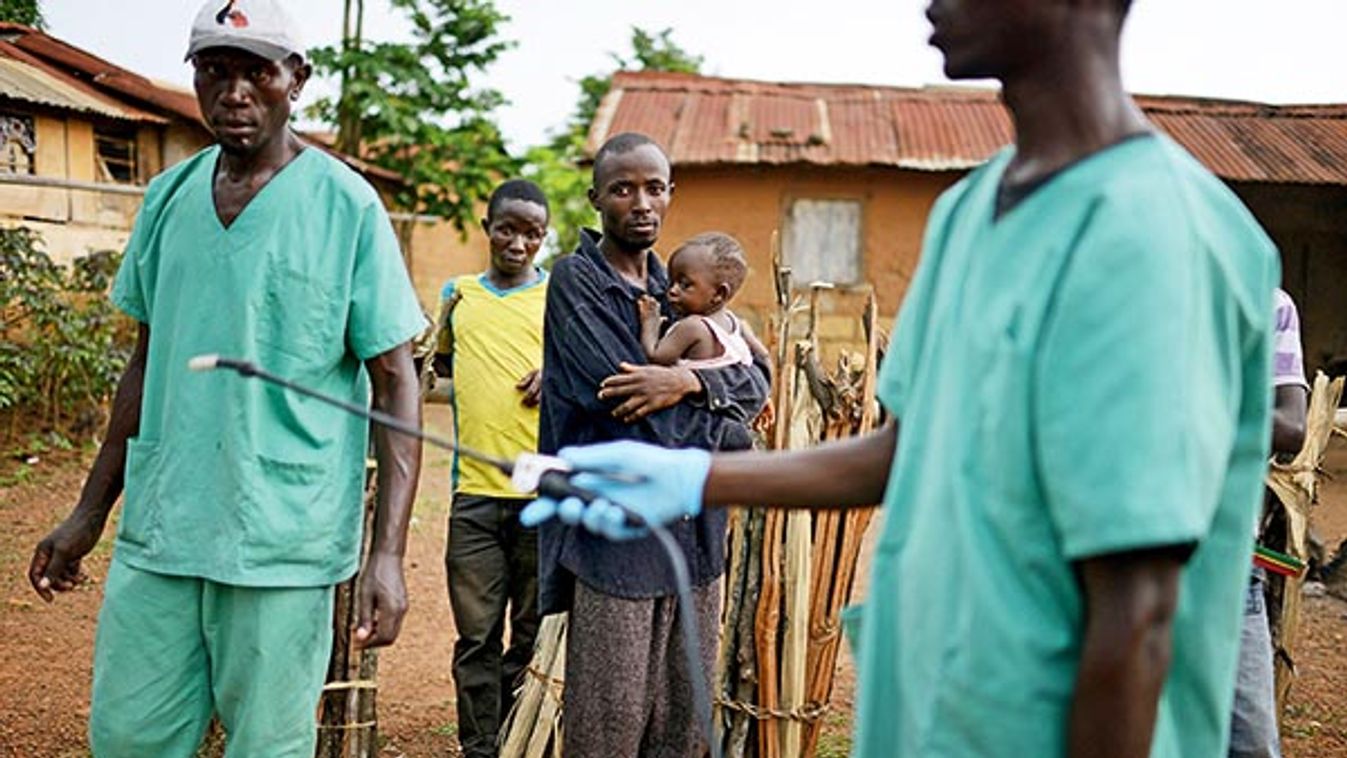 Locals watch workers with Doctors Without Borders as they disinfect after leaving a private clinic working to combat the spread of the Ebola virus in