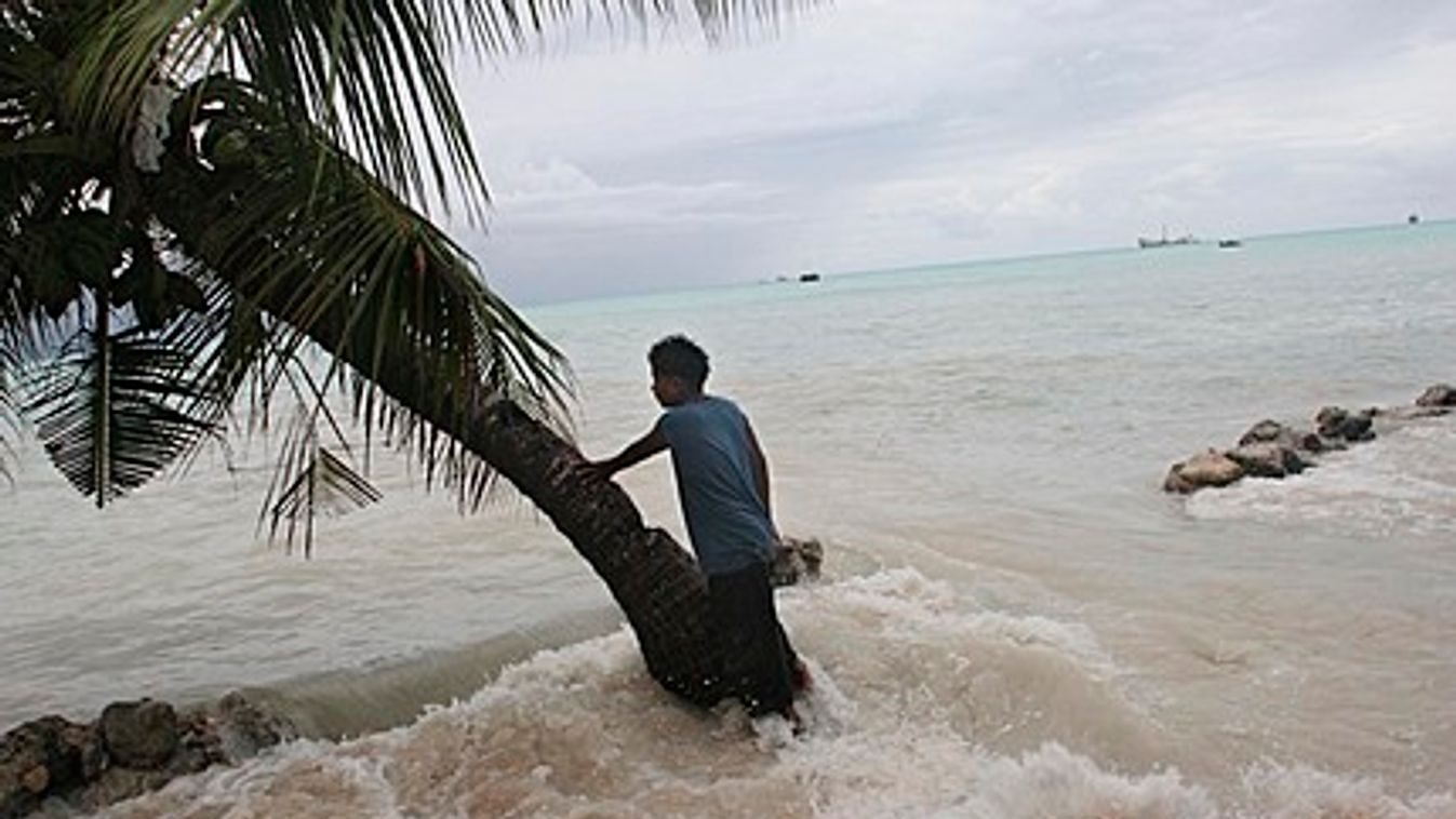 Pita Meanke, of Betio village, stands beside a tree as he watches the 'king tides' crash through the sea wall his family built onto his family property, on the South Pacific island of Kiribati.