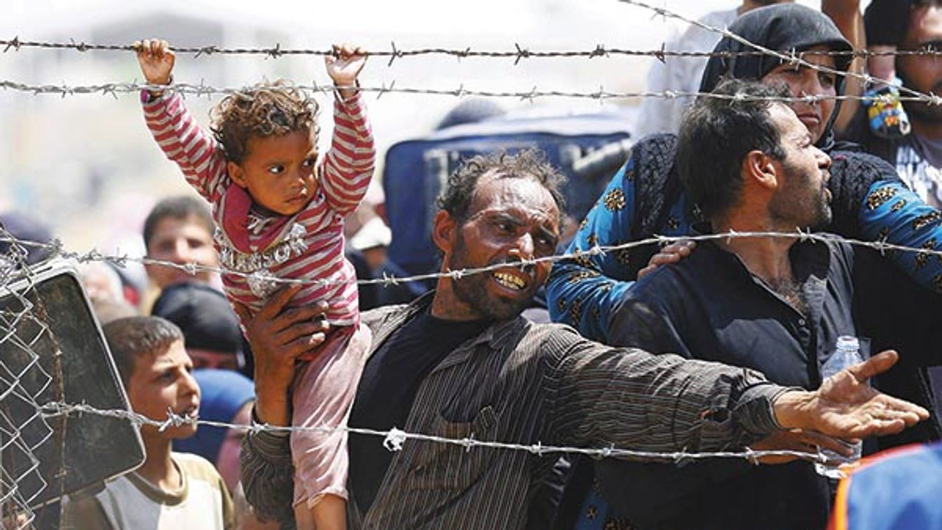 A Syrian refugee reacts as he waits behind border fences to cross into Turkey at Akcakale border gate in Sanliurfa province, Turkey