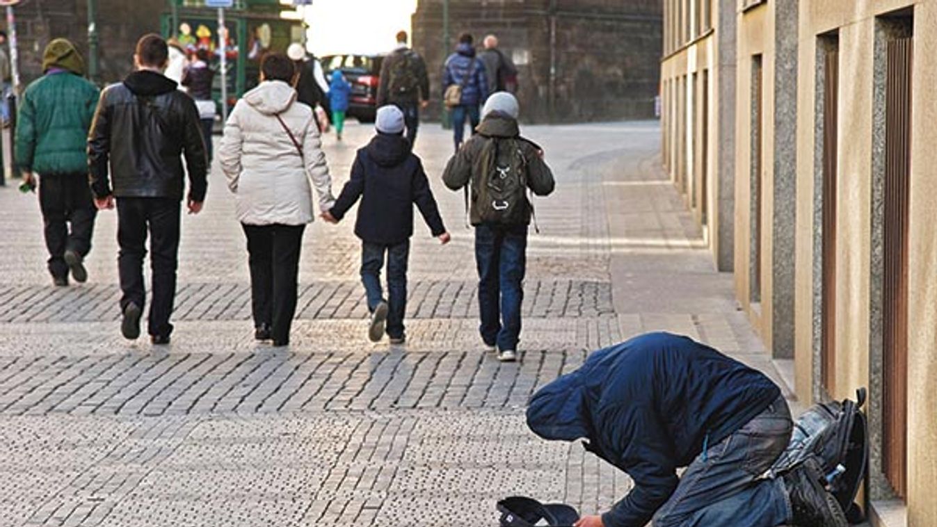 Prague. Czech Republic. April 2012. A homeless man begs on the street as people walk by indifferent