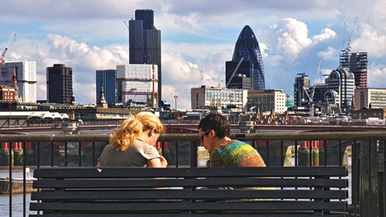 two people sitting talking on a bench on the South bank opposite the City of London with the skyscra