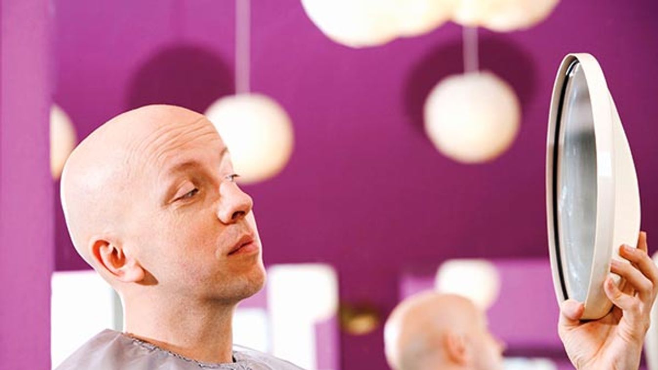 bald man at hair salon looking into mirror