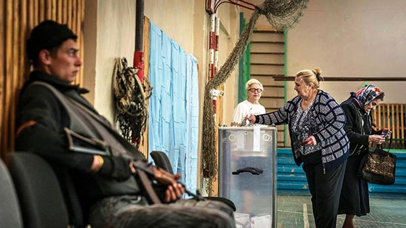 Residents cast their ballots on the autonomy referendum as a rebel guards the polling station in Slovyansk, Ukraine.