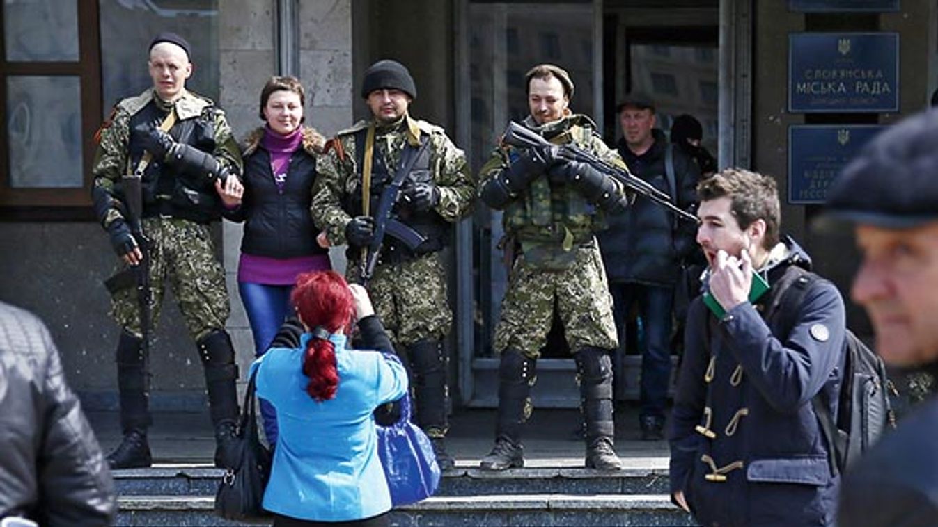A local resident poses for a picture with pro-Russian armed men standing guard outside the mayor's office in Slaviansk