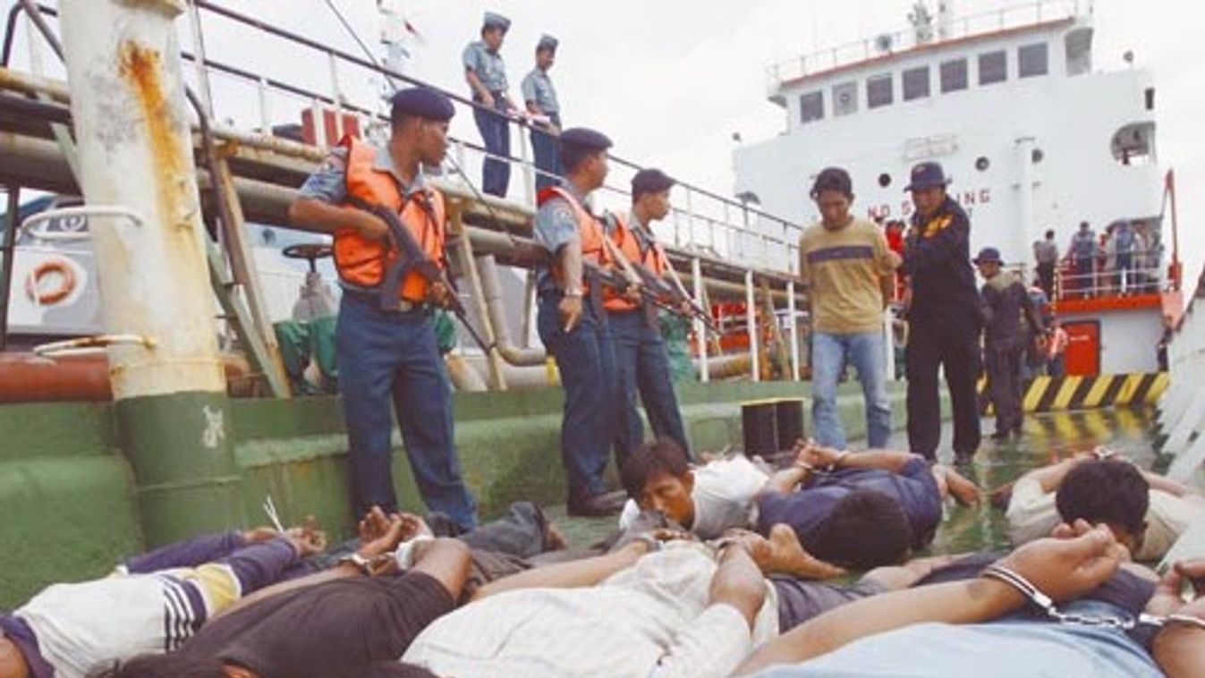 Indonesia navy personnel hold their rifles as a group of pirates lie on the deck of a crude palm oil tanker in the Straits of Singapore