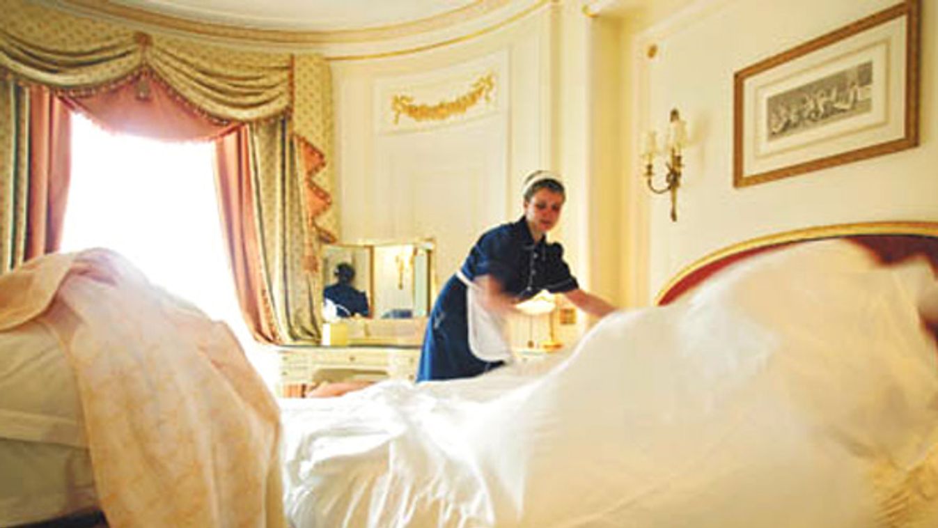 A chambermaid changes the sheets on a bed at The Ritz in London