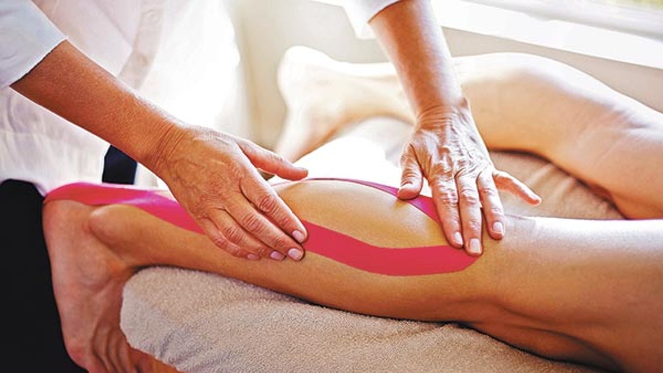 Physical therapist applying kinesiology tape to man’s leg