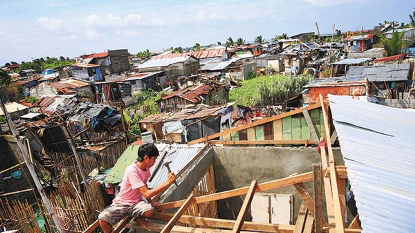 A man fixes the roof of his home after a Tornado and torrential rains downpour brought by the monsoon rains battered a residential area in Baseco, Tondo city, metro Manila 