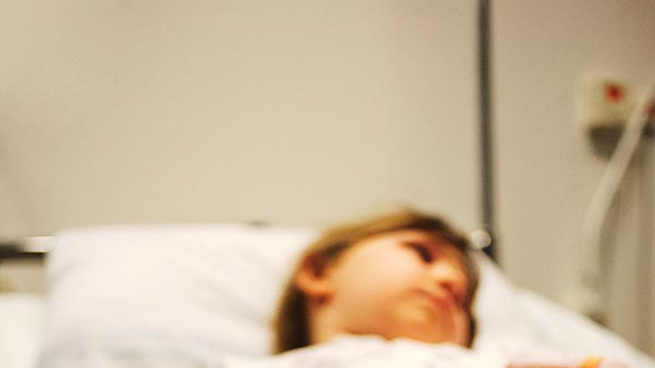 Girl lying on hospital bed with IV drip on arm