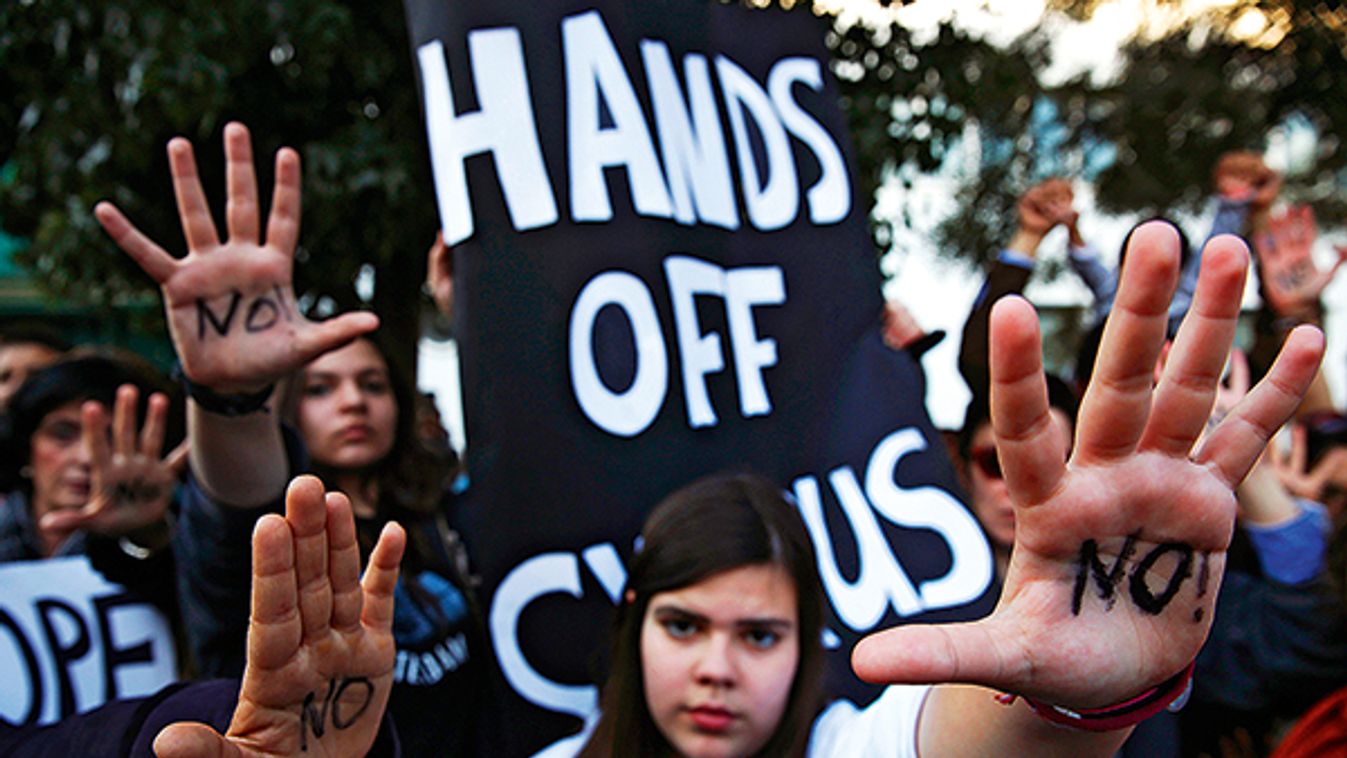 Protesters raise their open palms showing the word "No" during an anti-bailout rally in Nicosia