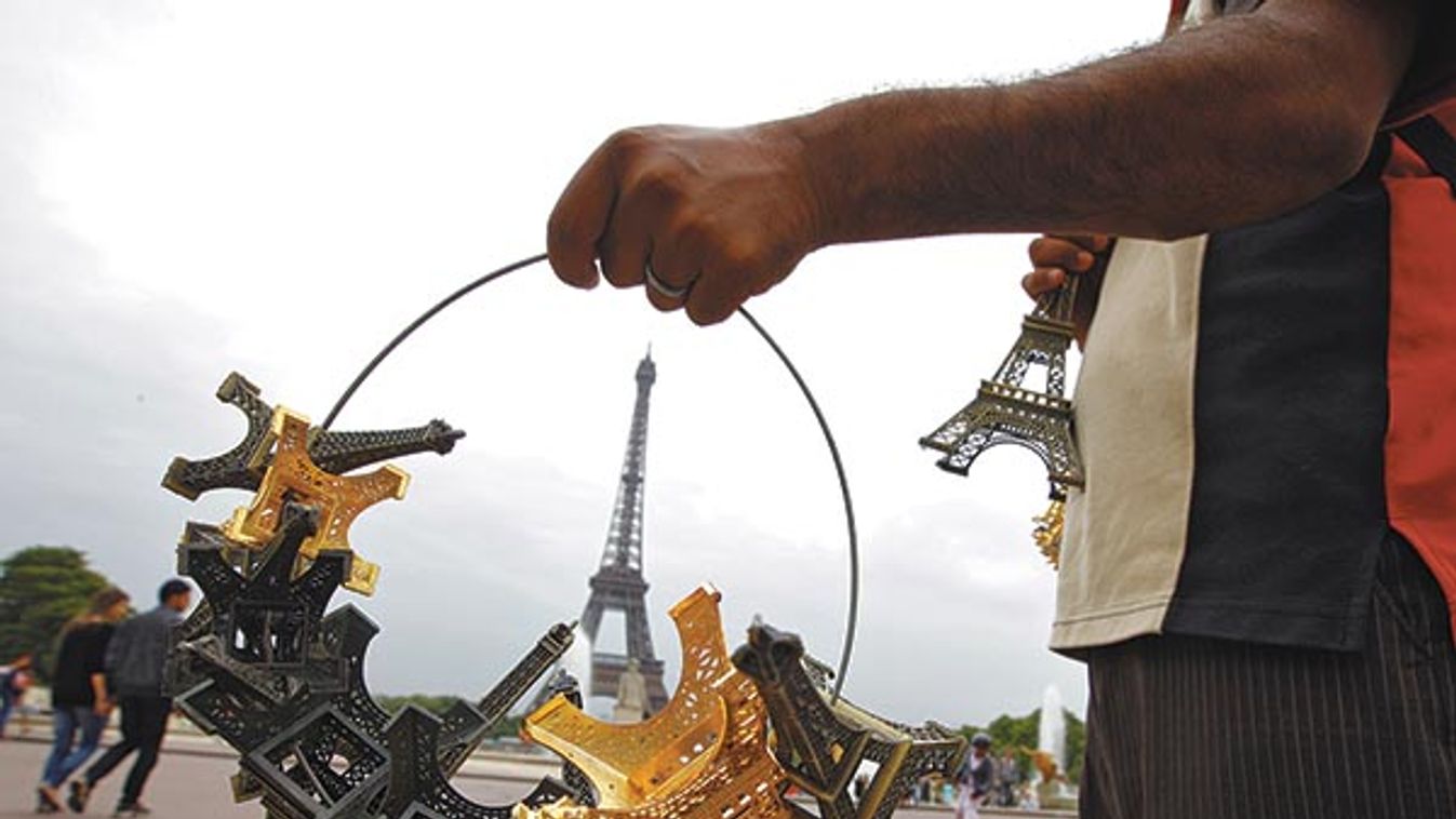 A souvenir vendor sells Eiffel tower models for tourists in front the Eiffel tower at the Trocadero in Paris