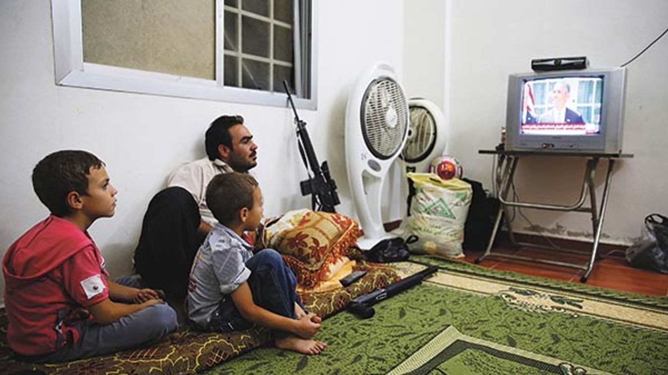 A Free Syrian Army fighter watches U.S. President Barack Obama's speech with his family in Damascus