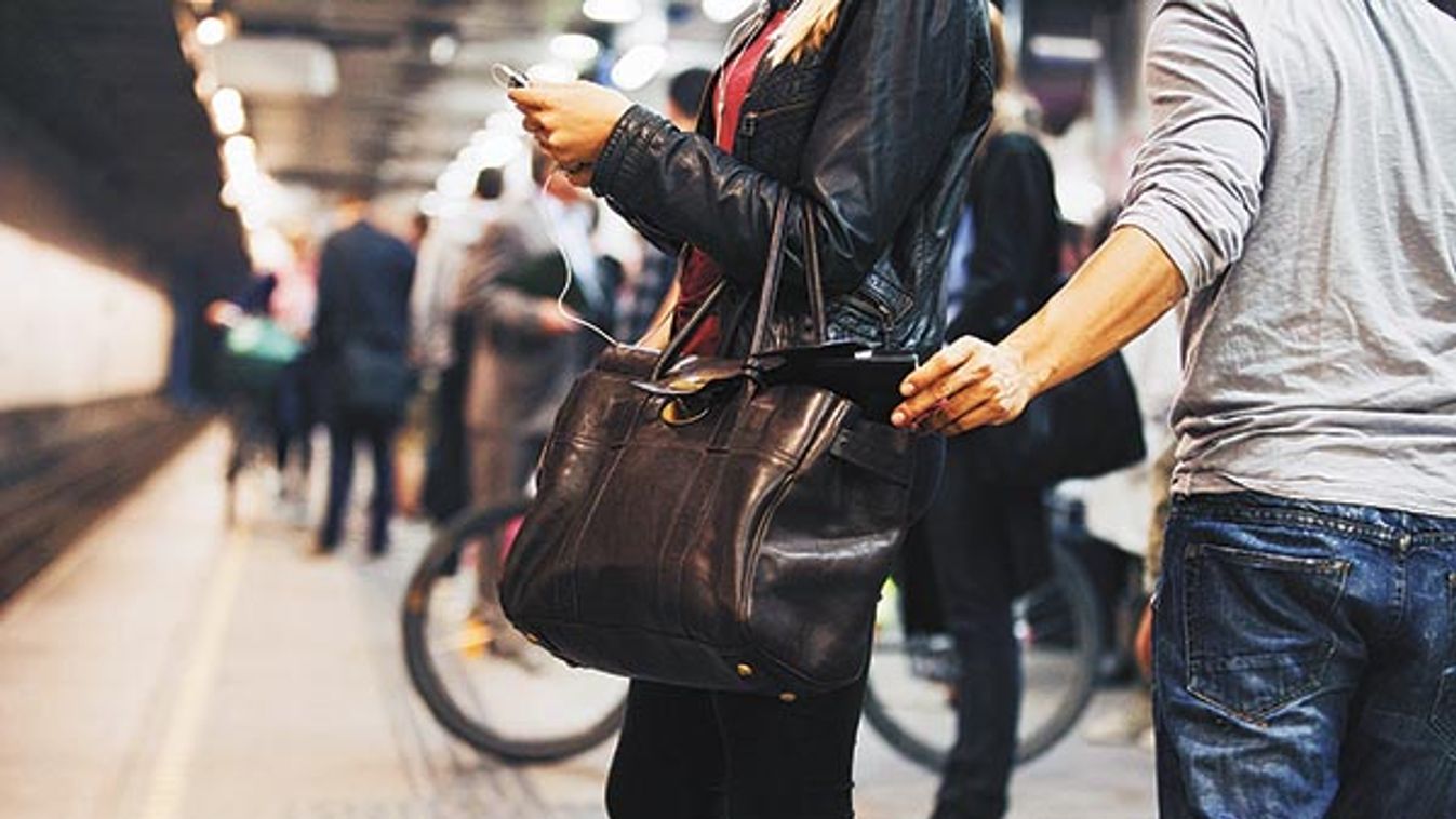 Young woman using mobile phone being robbed by a pickpocket at the subway station. Pickpocketing at