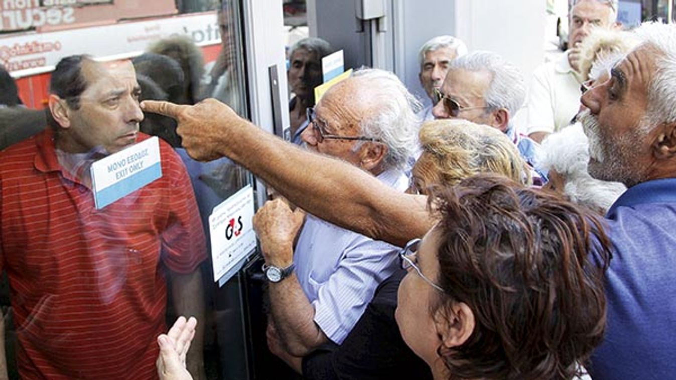 Pensioners waiting outside a closed National Bank branch and hoping to get their pensions, argue with a bank employee in Iraklio on the island of Crete