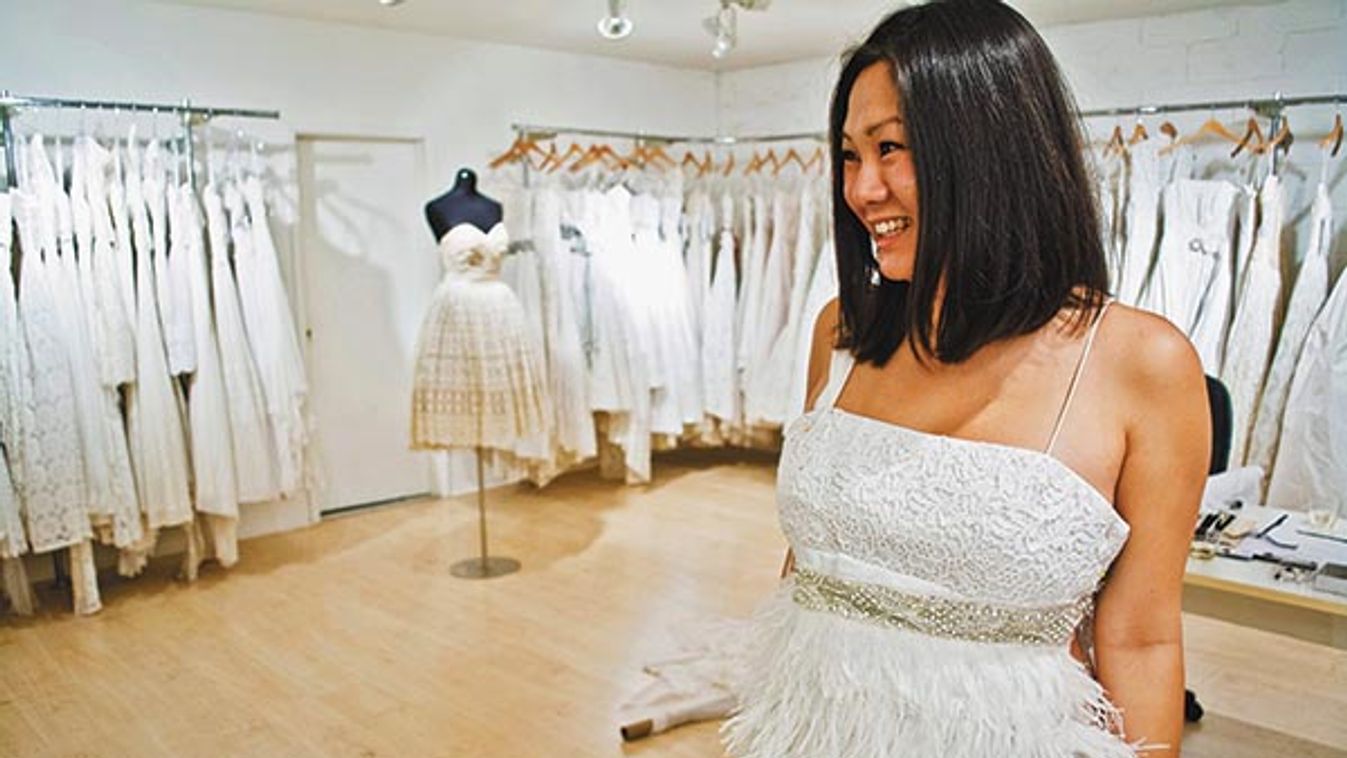 Mid adult woman trying on white feathered wedding dress