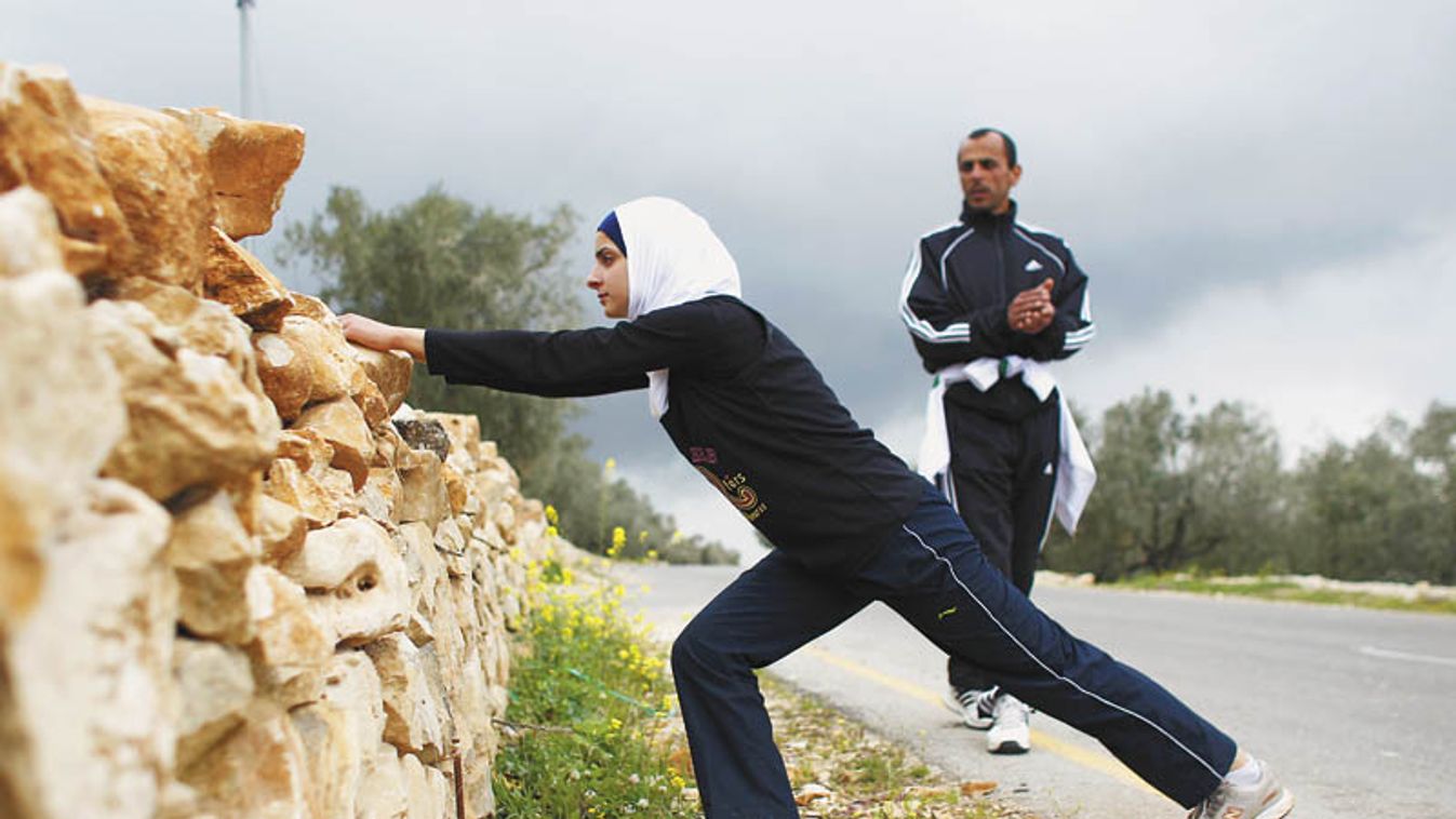 Palestinian runner Maslaha stretches as she practises with her trainer Jura near Nablus