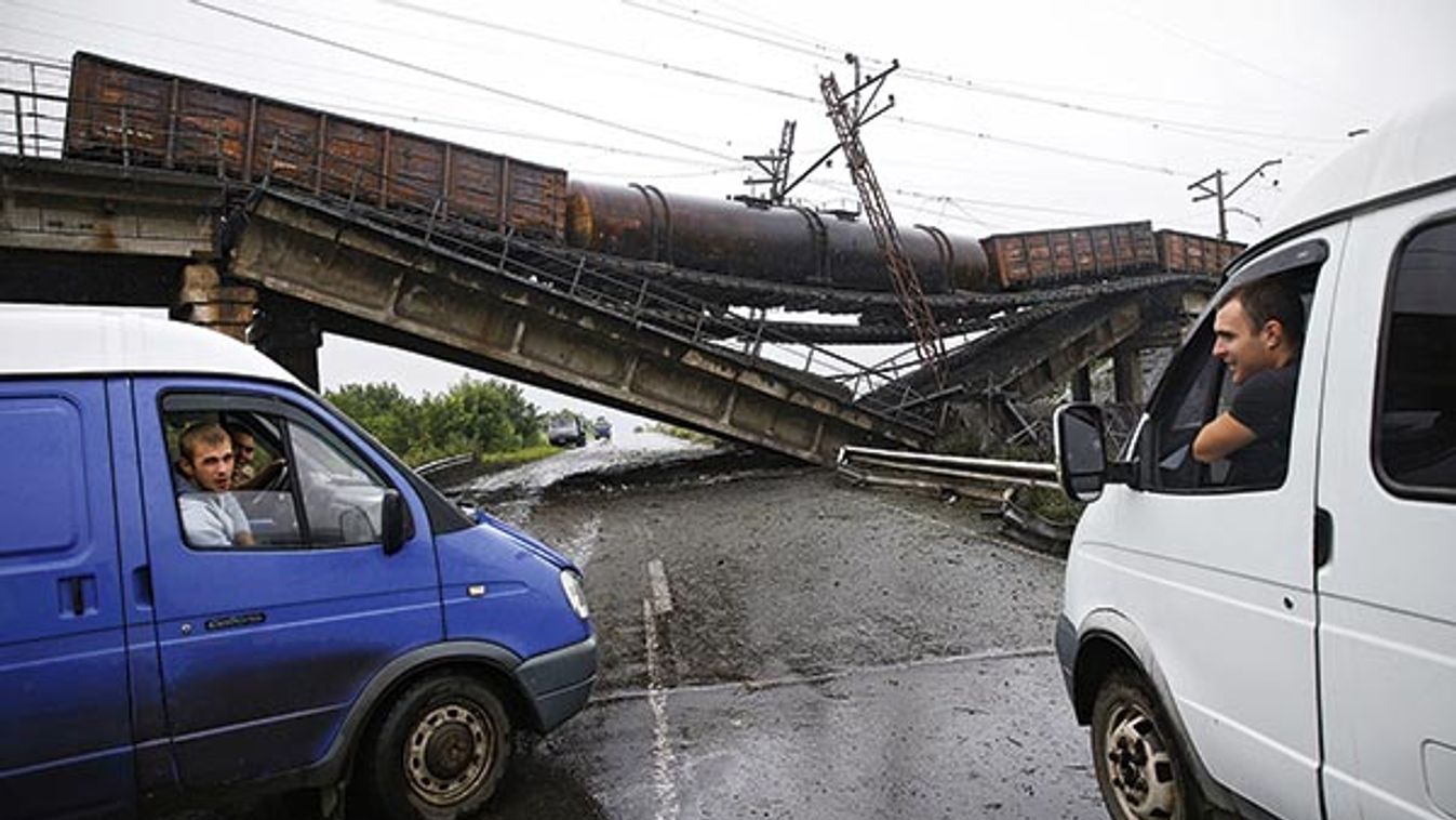 Drivers chat from their vehicles near a destroyed railroad bridge which fell over a main road leading to the eastern Ukrainian city of Donetsk, near the village of Novobakhmutivka